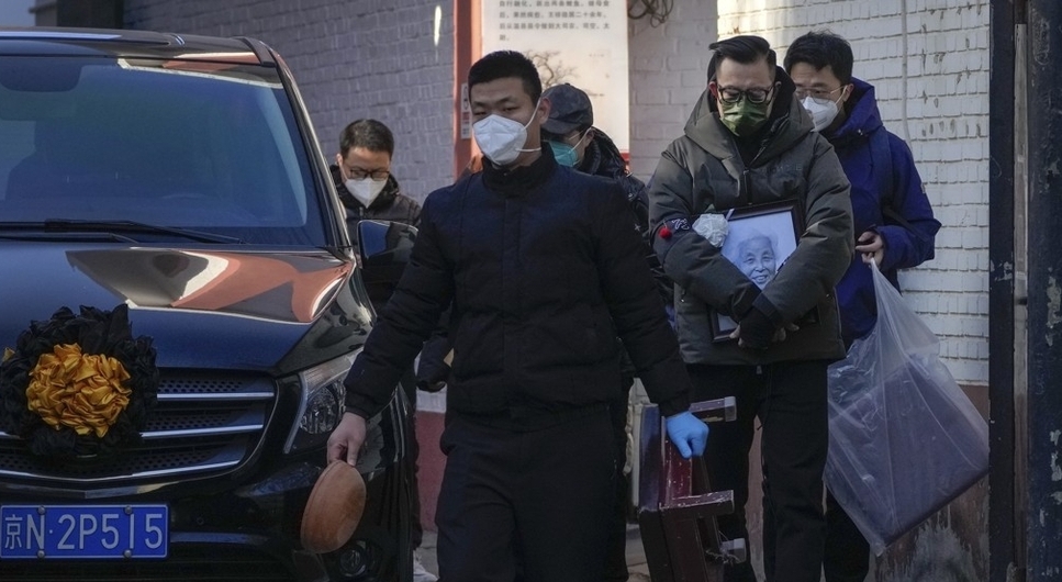 19일 중국 베이징의 한 발열 진료소 밖에서 영정 사진을 든 유족들이 시신을 운반하는 영구차 옆을 지나가고 있다. 중국정부의 코로나사망자 집계가 현실과 동떨어진 것이라는 비판을 받고 있다. /연합뉴스.